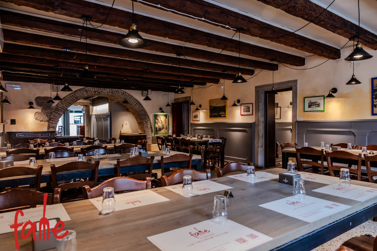 La sala FAME con grandi tavoli, travi in legno e quadri alle pareti